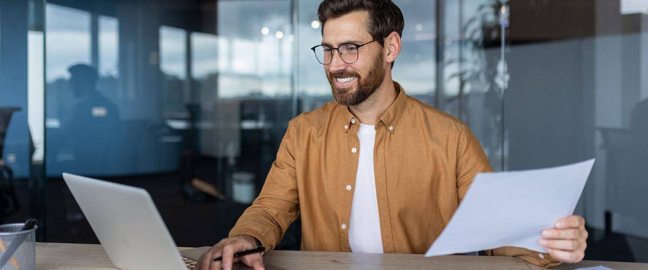 smiling man with glasses working on laptop
