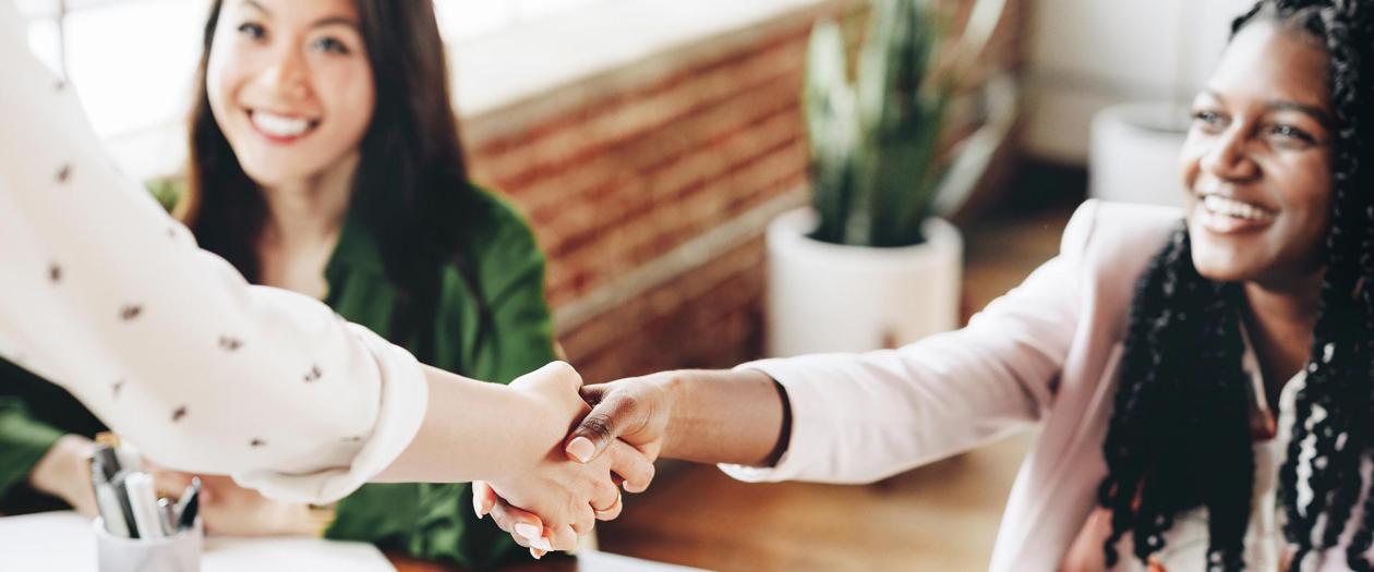 professionally dressed women shaking hands
